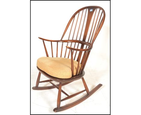 An Ercol beech and elm 20th century large comb back Windsor pattern rocking chair / armchair. Raised on turned legs united by