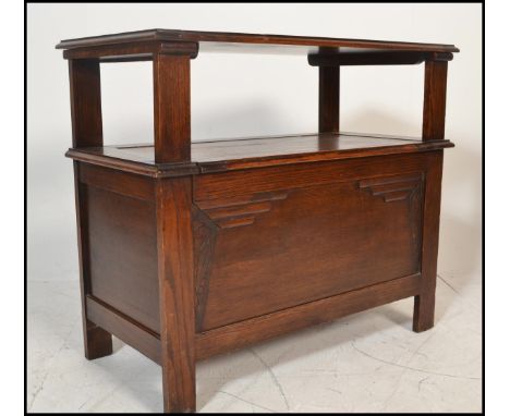 A 1920's oak monks bench / hall settle. Of plain form with stile legs having hinged seat with a fold over top supported by pa