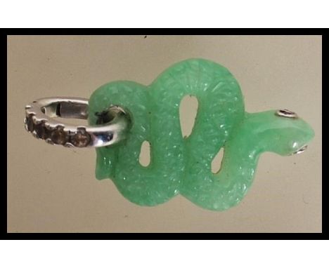 A carved jade pendant in the form of a snake having ruby and silver eyes on a silver 925&nbsp;pendant loop set with white sto