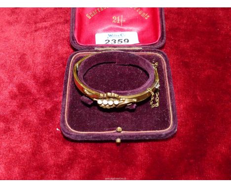 An elegant Art Nouveau style gilded hinged bangle with safety chain having four opalescent stones, in a mauve box.