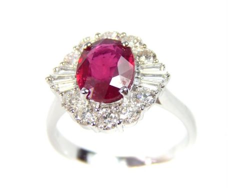 A boxed 18 ct white gold ruby and diamond cluster ring, the central faceted oval ruby is claw-set and framed by a coronet clu