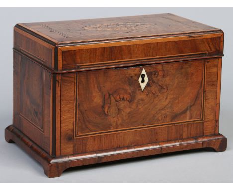 A Regency figured walnut inlaid tea caddy raised on bracket feet. With inlaid shell patera and ivory escutcheon, 25cm wide.  