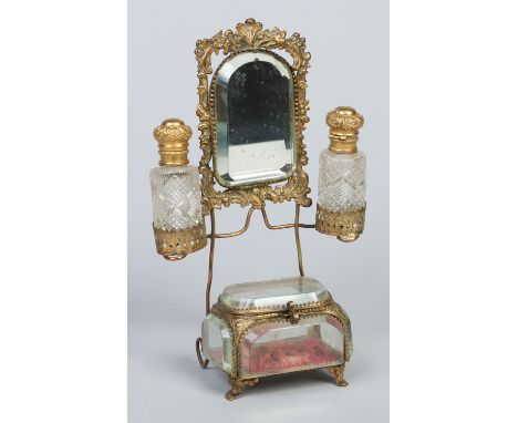 A Continental gilt brass trinket box formed as a dressing table. With a bevelled mirror and mounted with a pair of cut glass 