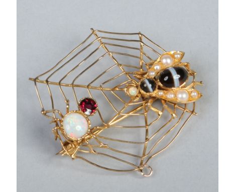 A novelty yellow metal spider web brooch / pendant with a gem set spider and fly adorned with tigers eye, seed pearls, garnet