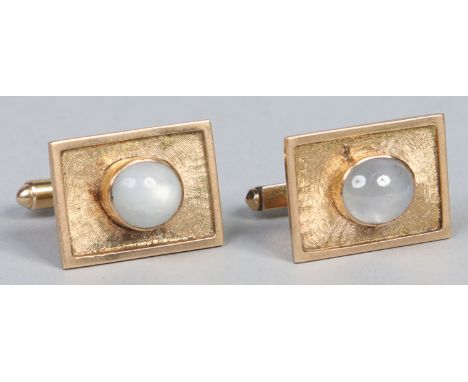 A pair of 14 carat gold cufflinks. Each set with a cabochon moonstone on a textured rectangular ground, 12.49 grams gross wei