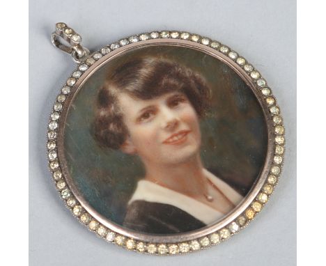 A George V mourning pendant with over painted photograph portrait miniature under a border of white paste stones. Dated 1916,