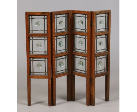 An oak framed four fold fire screen housing twelve leaded glass bulls eye panels, 76cm high. Condition Report. To be used as 