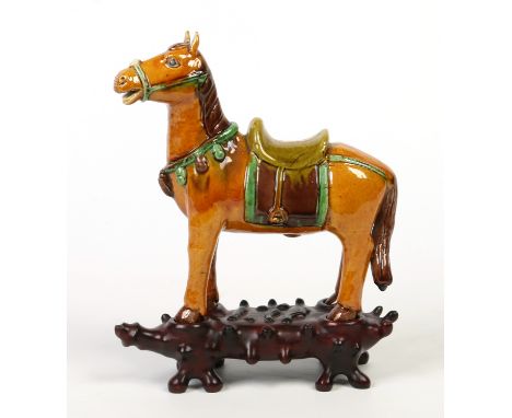 A Chinese glazed earthenware model of a horse raised on a well carved hardwood base, 25.5cm high.  Condition Report. To be us