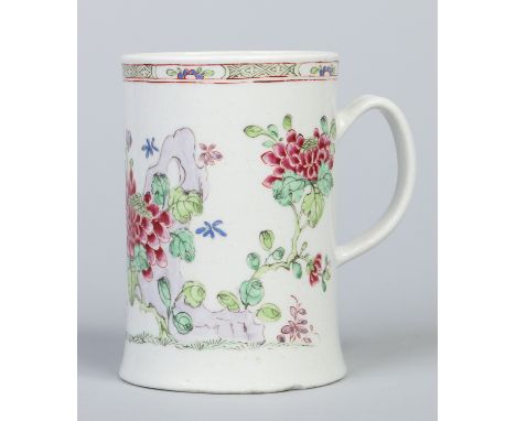 A large Bow mug of cylindrical form, with reeded strap handle and spreading foot. Decorated in the famille rose palette with 