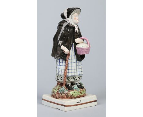 A 19th century pearlware titled figure, Age. Formed as an old woman wearing a bonnet and shawl and carrying a basket supporte