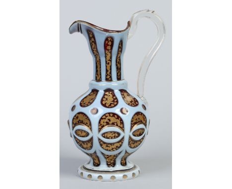 A 19th century Bohemian ruby glass jug. With white opaque overlay decoration with cut panels gilded with foliage, 30.5cm. Con