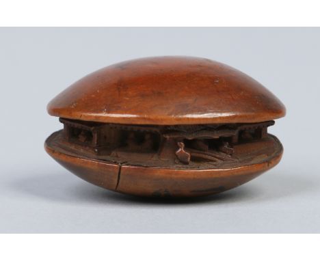 A Japense carved fruitwood netsuke. Formed as a clam shell containing a miniature village scene, 4.75cm wide.  Condition Repo