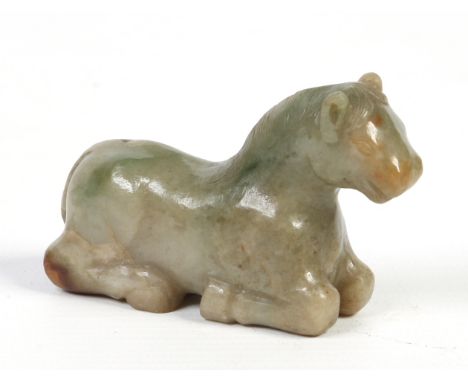 A Chinese pale jade model of a recumbent horse carved with mane and tail detail and having russet suffusions, 7cm. Condition 