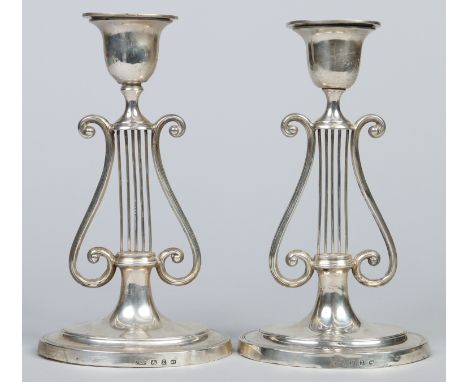 A pair of Victorian silver candlesticks by J. R. Ltd. With detachable oval nozzles, raised on openwork lyre pedestals over ov