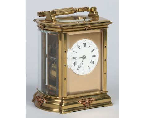 A brass bow sided carriage clock with platform escapement and repeating mechanism striking on a gong. With gilt mask and enam