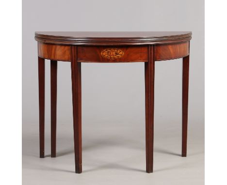 A George IV mahogany fold over bow front tea table with inlaid shell patera and raised on tapering reeded supports, 91cm wide