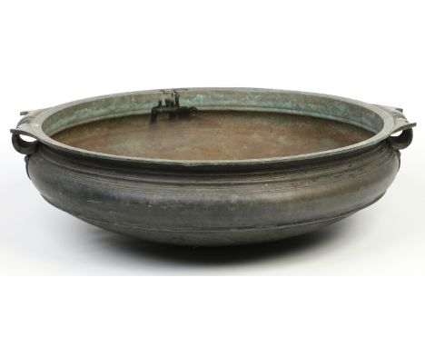 A large 19th century South Indian copper alloy Charakku (temple basin) of shallow circular form and with large stylized loop 