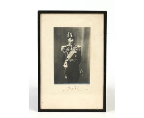 A framed monochrome photograph, three quarter length portrait of H. M. King George V in full naval uniform. Autographed at th