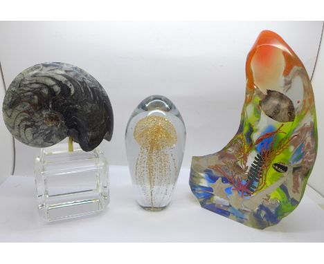 A polished fossil on stand, a glass paperweight and a resin sea life paperweight 