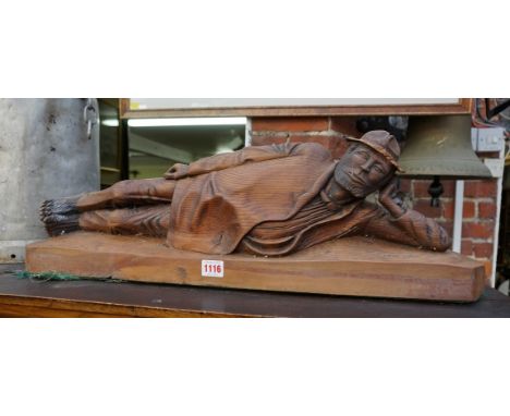 A carved pitch pine reclining figure, signed 'R McD' and dated 9/91, 69cm wide, (chips to brim of hat). 