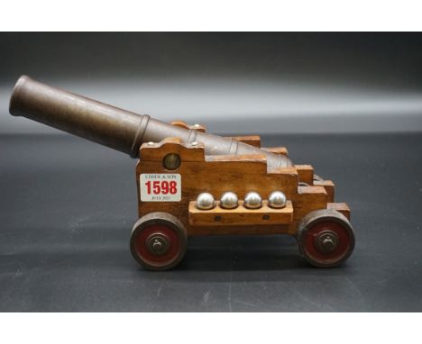 A bronze desk cannon, on beech four wheel carriage,&nbsp;the cannon 25.5cm long. 