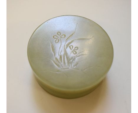 A Chinese celadon jade circular box and cover, the top carved with floral decoration, 5.8cm diameter. 