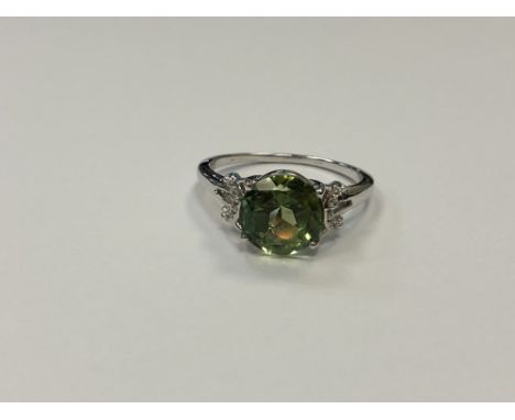 A silver dress ring set with a green stone, size T1/2