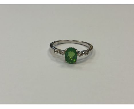 A silver dress ring set with a green stone, size T