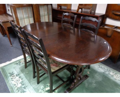 An oval oak dining table with one leaf and four ladder back chairs 