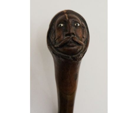 A 19th Century walking stick, the rootball handle carved as  man with a large moustache, inset glass eyes, knobby briar wood 