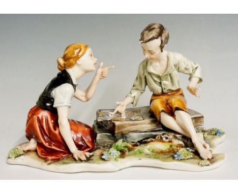 A Naples porcelain figure group of two children playing a board game seated on slabs and shaped rustic base, 21cm wide, 13cm 