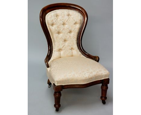 A late Victorian  button back nursing chair, moulded frame on turned tapered legs fitted ceramic castors, upholstered in pale
