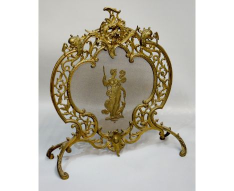 A cast brass fireguard of pierced cartouche form decorated with stylised sea serpents, scrolls, leafage and rococo cartouche 