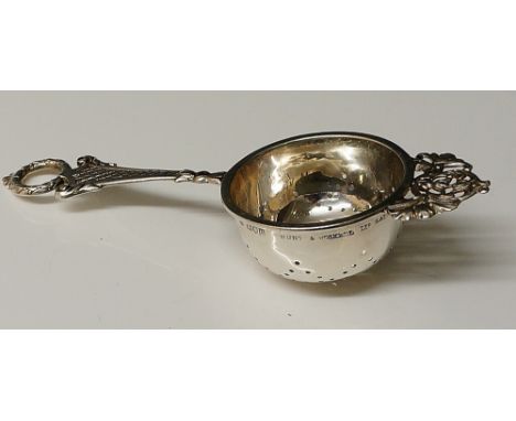 Paul Storr - a silver tea strainer, the handle with wreath finial above diamond hatched handle, pierced and foliate engraved 