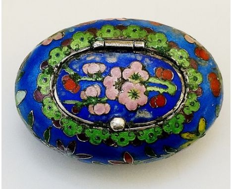 A Chinese oval silver and enamel snuff or pill box the hinged lid decorated with pink blossom within green and red flowerhead