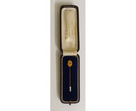 A 15ct gold and sapphire stick pin, the shaped top centred on a small sapphire on an oval raised tablet with wire and frilled