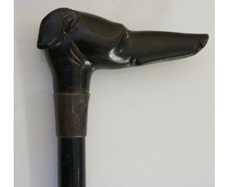 An early 20th Century walking stick, the ebonised handle carved as a Whippet's head, inset amber glass eyes, plain silver fer