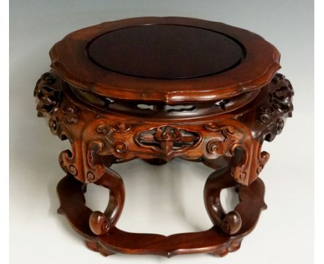 A Chinese hardwood vase stand the shaped panelled circular top above a pierced and carved frieze on scrolling legs with flatt