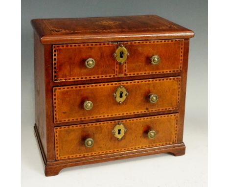 A George II miniature walnut chest of drawers, the top with parquetry centre within conforming parquetry bands, the drawers c