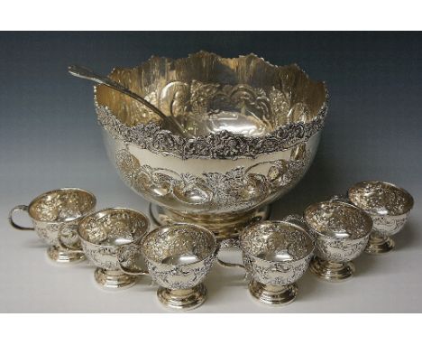 A silver plated punch bowl with six matching cups, all chased and embossed with scrolls and foliage, the cups with folded ove
