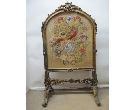 A very ornate Victorian gilt gesso firescreen with scrolled, leaf ornament and an embroidered, bead and raised wool tapestry 