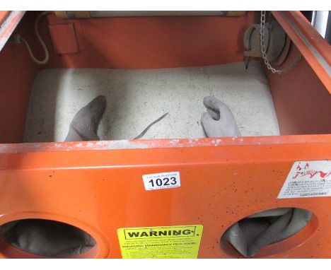 A cabinet sandblaster with various grades of blast media and a bench
