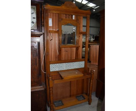 A late Victorian light stained hallway hat cloak and coat stand having tiled back and mirror centre panel