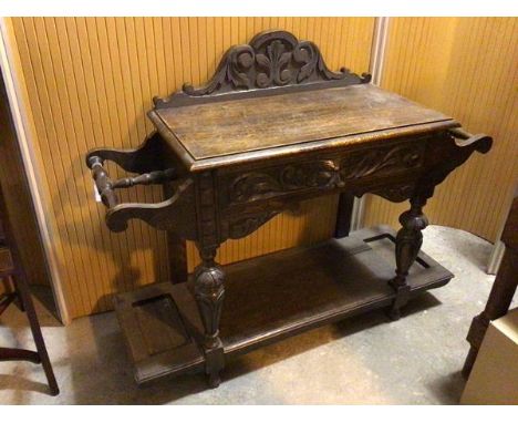 A 1920s/30s oak hall table, with foliate crest above a rectangular top with moulded edge, stick stands to either side, lackin