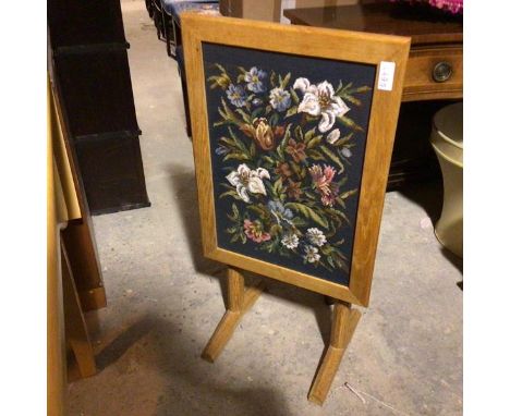 An oak firescreen/occasional table, the floral grospoint panel within a frame, can tilt and lock back creating table top, on 