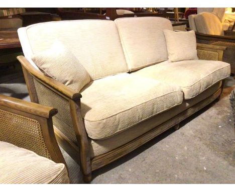 An Ercol three seater sofa with caned sides and cushions in sand corduroy upholstery, stamped Ercol (82cm x 190cm x 100cm)