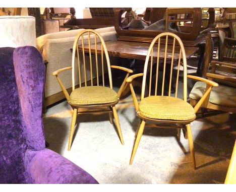 A pair of Ercol beech and elm armchairs, with hoop and spindle backs, upholstered seat cushions and turned supports, stamped 