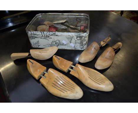 Assorted vintage shoe trees including adjustable metal and wooden in a vintage tin.