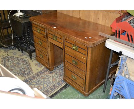 A late Victorian kneehole desk, recessed shelf to kneehole, an arrangement of seven drawers, campaign style brass handles, la