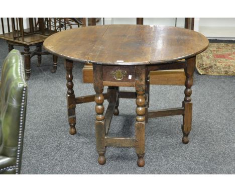 An early 18th century oak gate leg table, single drawer with brass batwing handle